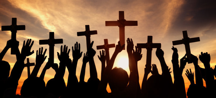 Group of People Holding Cross and Praying in Back Lit