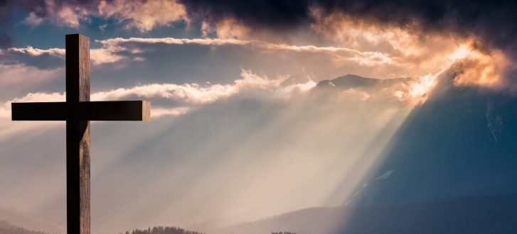 Jesus Christ wooden cross on a dramatic, colorful sunset
