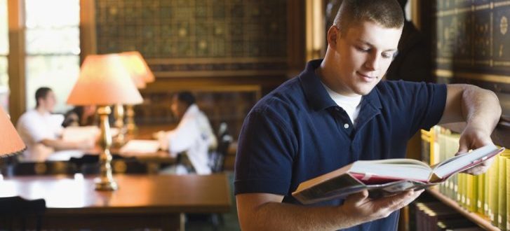 Student reading a book in a library