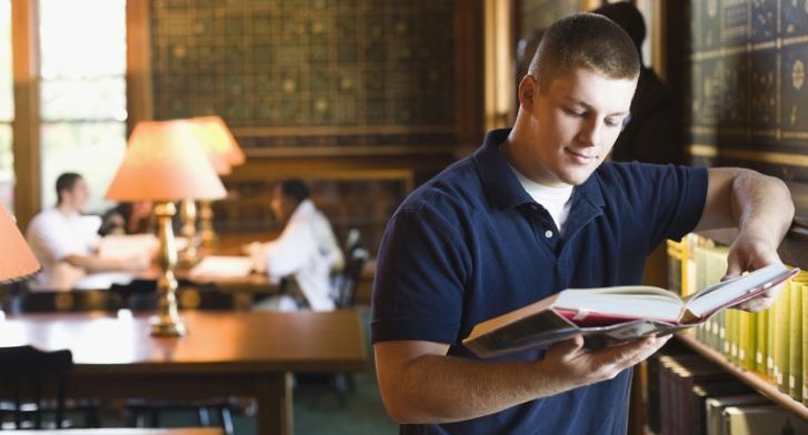 Student reading a book in a library